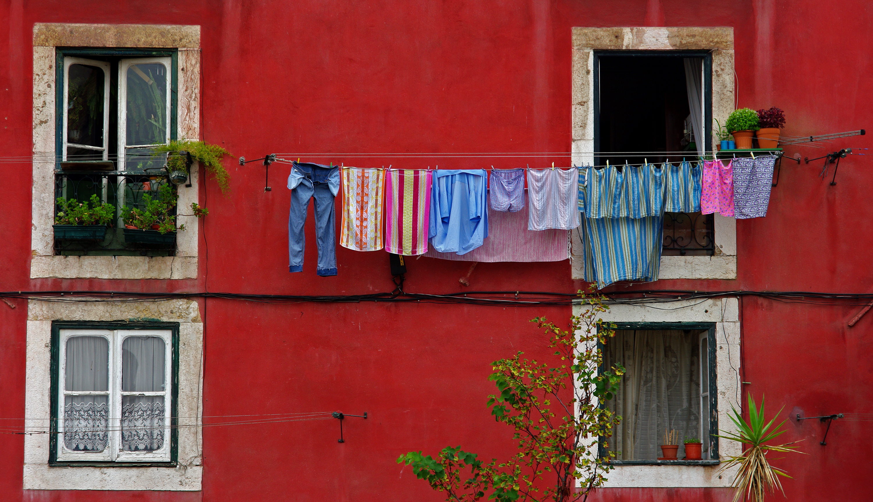 Farverig tøjvask hængt til tørre udenfor traditionelle bygninger i Lissabons gamle kvarterer
