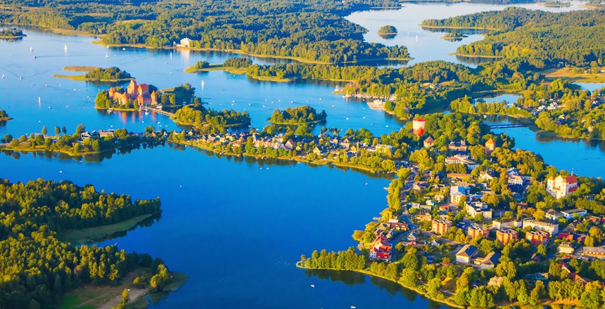 Betagende luftfoto af det middelalderlige Trakai-slot på en ø i den blå Galve-sø i Litauen, med sine karakteristiske røde murstensmure og tårne omgivet af skinnende vand