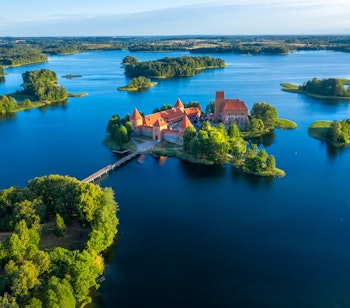 Betagende luftfoto af det historiske Trakai slot omgivet af blå søer i Litauen, et unikt middelalderslot på en ø med karakteristiske røde murstenstårne