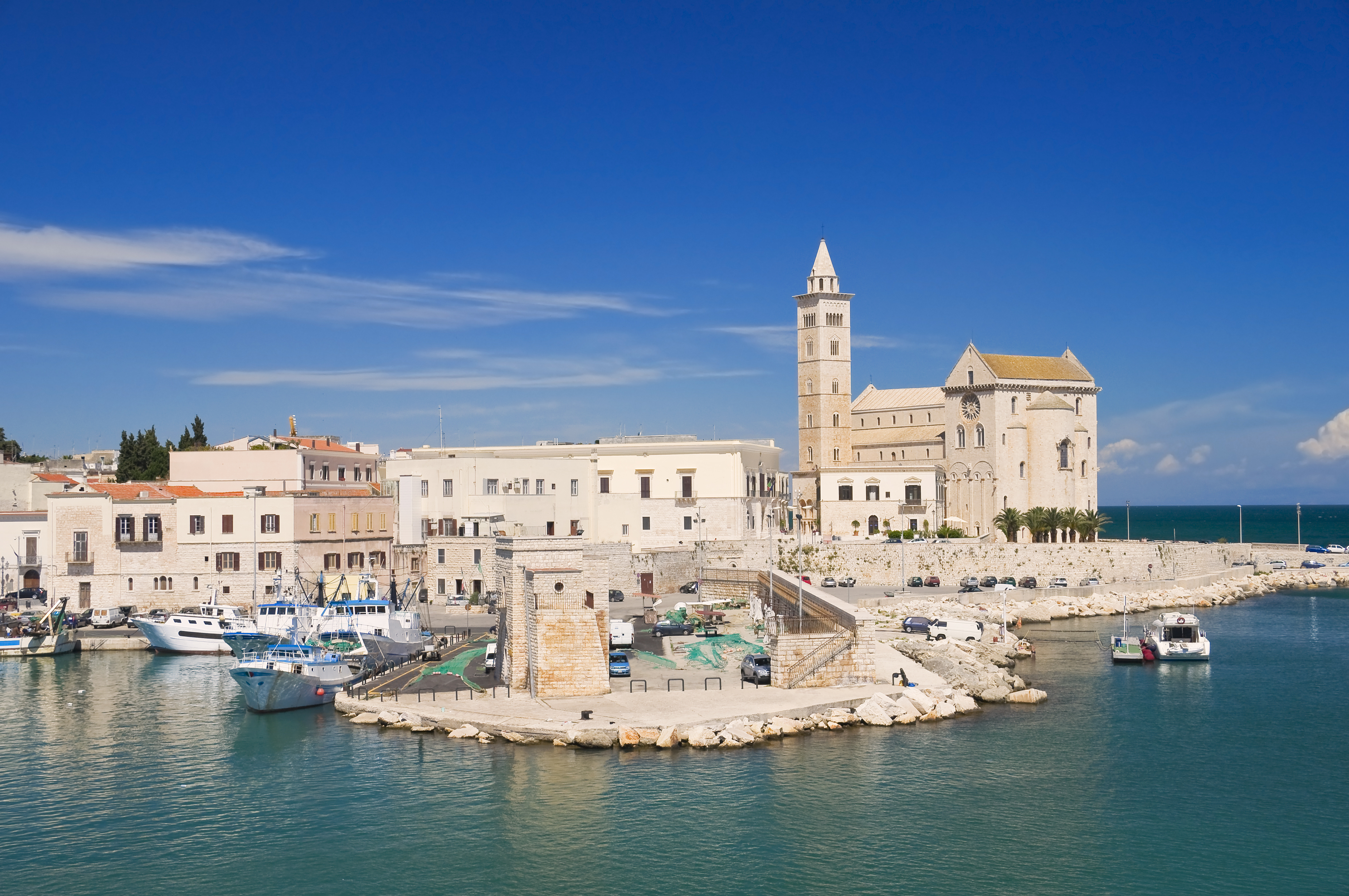 Den historiske katedral i Trani, Puglia med dens imponerende klokketårn spejler sig i det azurblå Adriaterhav på en solrig sommerdag i Syditalien.