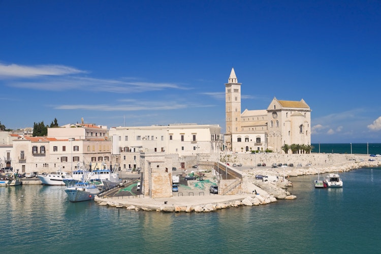 Den historiske katedral i Trani, Puglia med dens imponerende klokketårn spejler sig i det azurblå Adriaterhav på en solrig sommerdag i Syditalien.