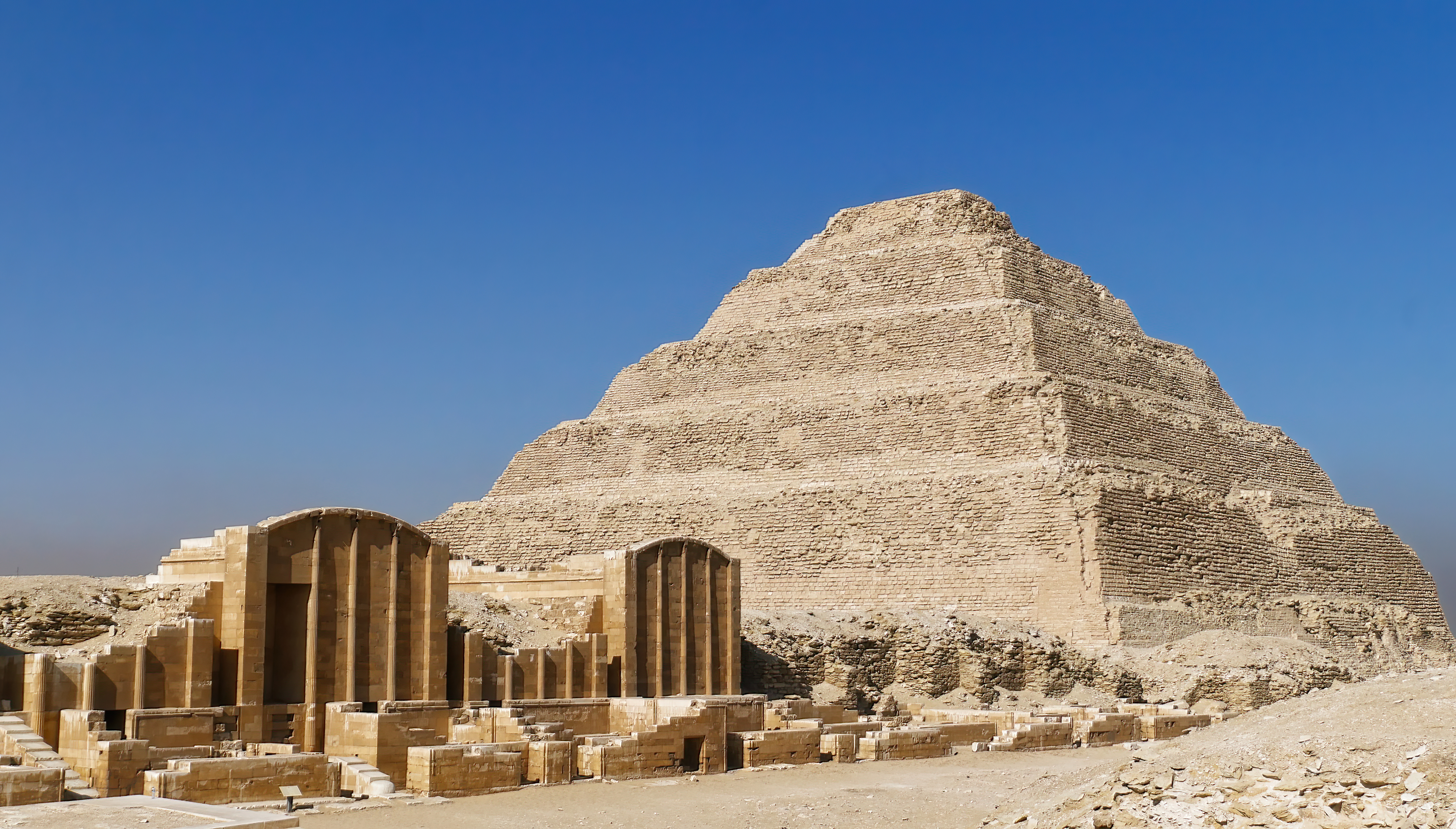 Trappepyramiden i Saqqara, Egyptens ældste pyramide bygget af farao Djoser, med antikke tempelruiner og søjler i forgrunden