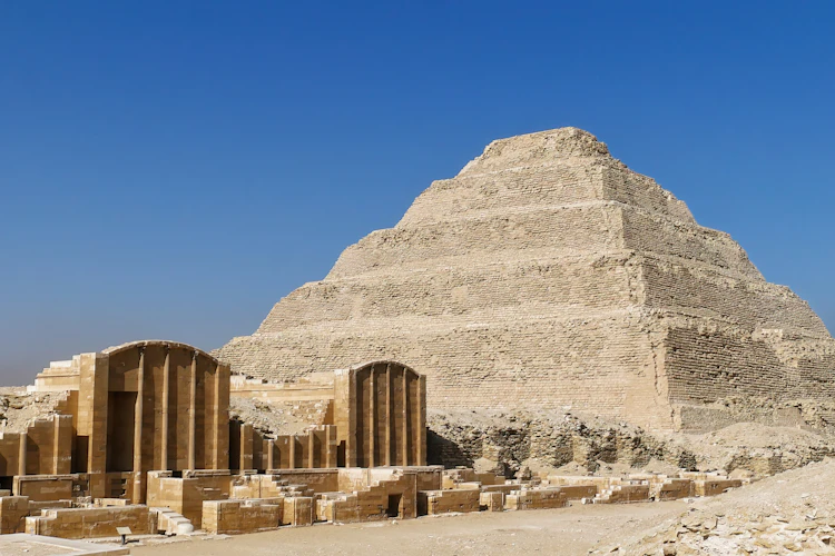 Trappepyramiden i Saqqara, Egyptens ældste pyramide bygget af farao Djoser, med antikke tempelruiner og søjler i forgrunden