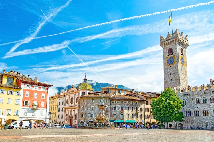 Den smukke Piazza Duomo i Trento, Italien, med Neptunfontænen, farverige renæssancebygninger og det historiske Torre Civica klokketårn