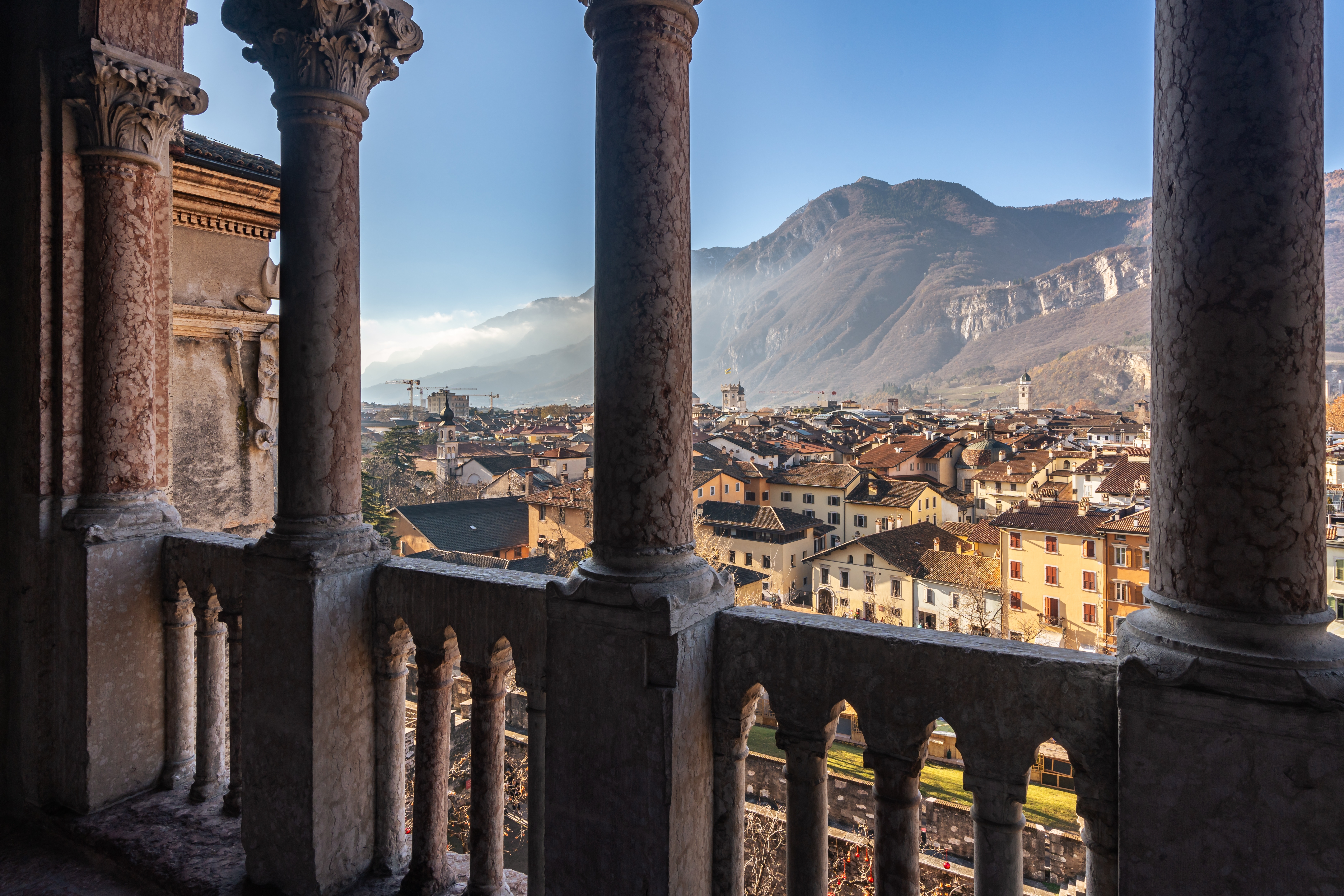 Panoramaudsigt over Trento by fra Castello del Buonconsiglio med smukke stensøjler og Alperne i baggrunden, Trentino, Italien