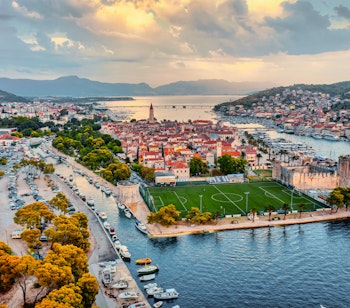 Luftfoto af Trogirs gamle bymidte med historisk arkitektur, lystbådehavn og azurblå kystlinje i Kroatien