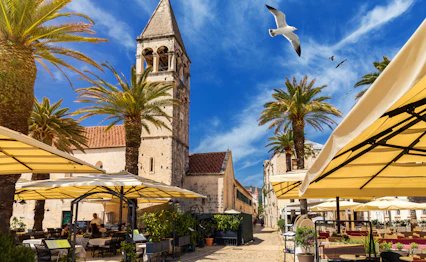 Historisk Trogir by med middelalderligt klokketaarn og udendoers restauranter i Kroatien