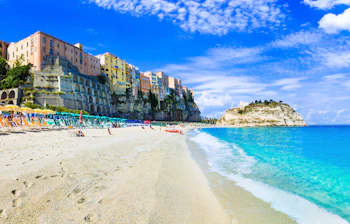 Smuk hvid sandstrand i Tropea, Calabrien med turkisblåt hav og farverige klippe bygninger i baggrunden på en solrig sommerdag