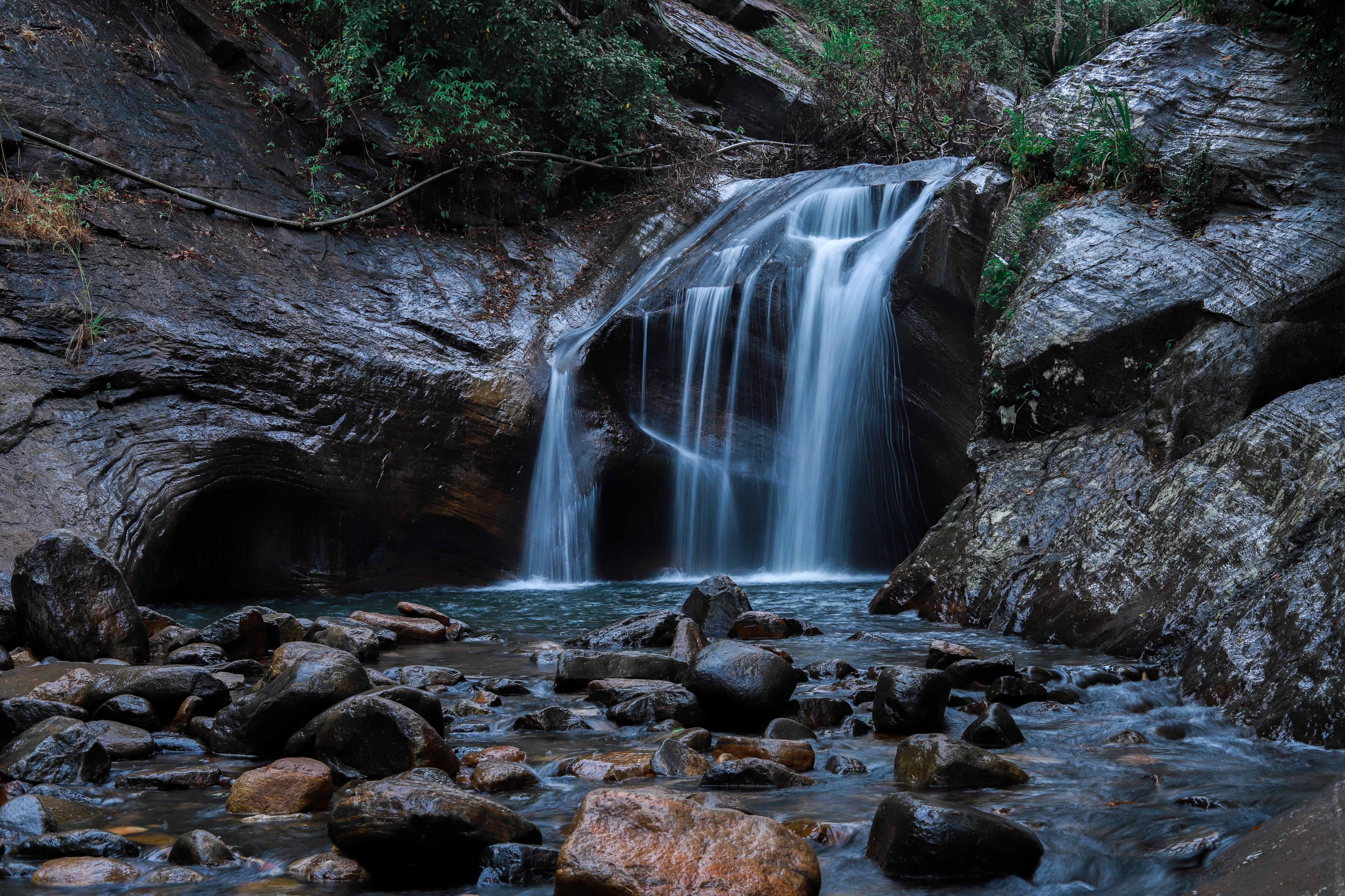 Smuk vandfald i tropisk skov med klipper og grønne træer