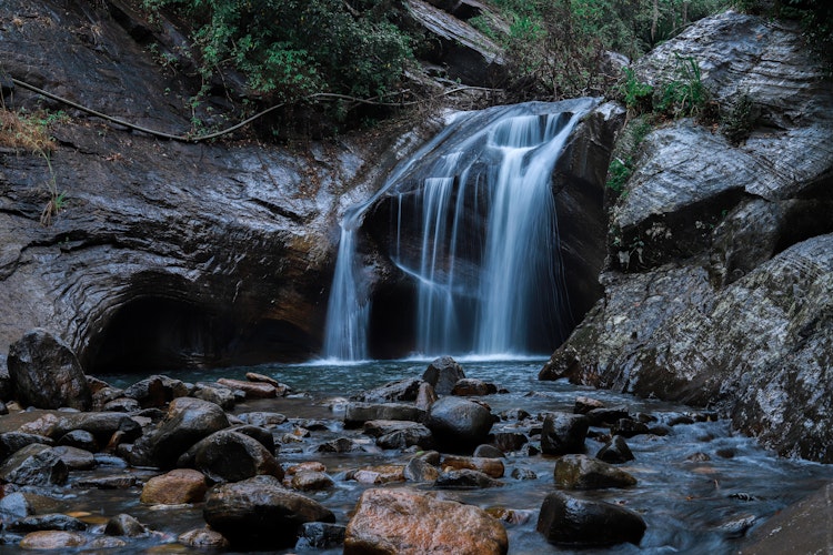 Smuk vandfald i tropisk skov med klipper og grønne træer