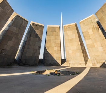 Tsitsernakaberd mindekomplekset for det armenske folkedrab i Yerevan med karakteristiske stensøjler og central spir mod en klar blå himmel
