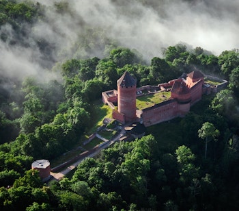 Imponerende luftfoto af det historiske Turaida-slot omgivet af grøn skov i Sigulda, Letland - et fascinerende middelalderligt kulturminde