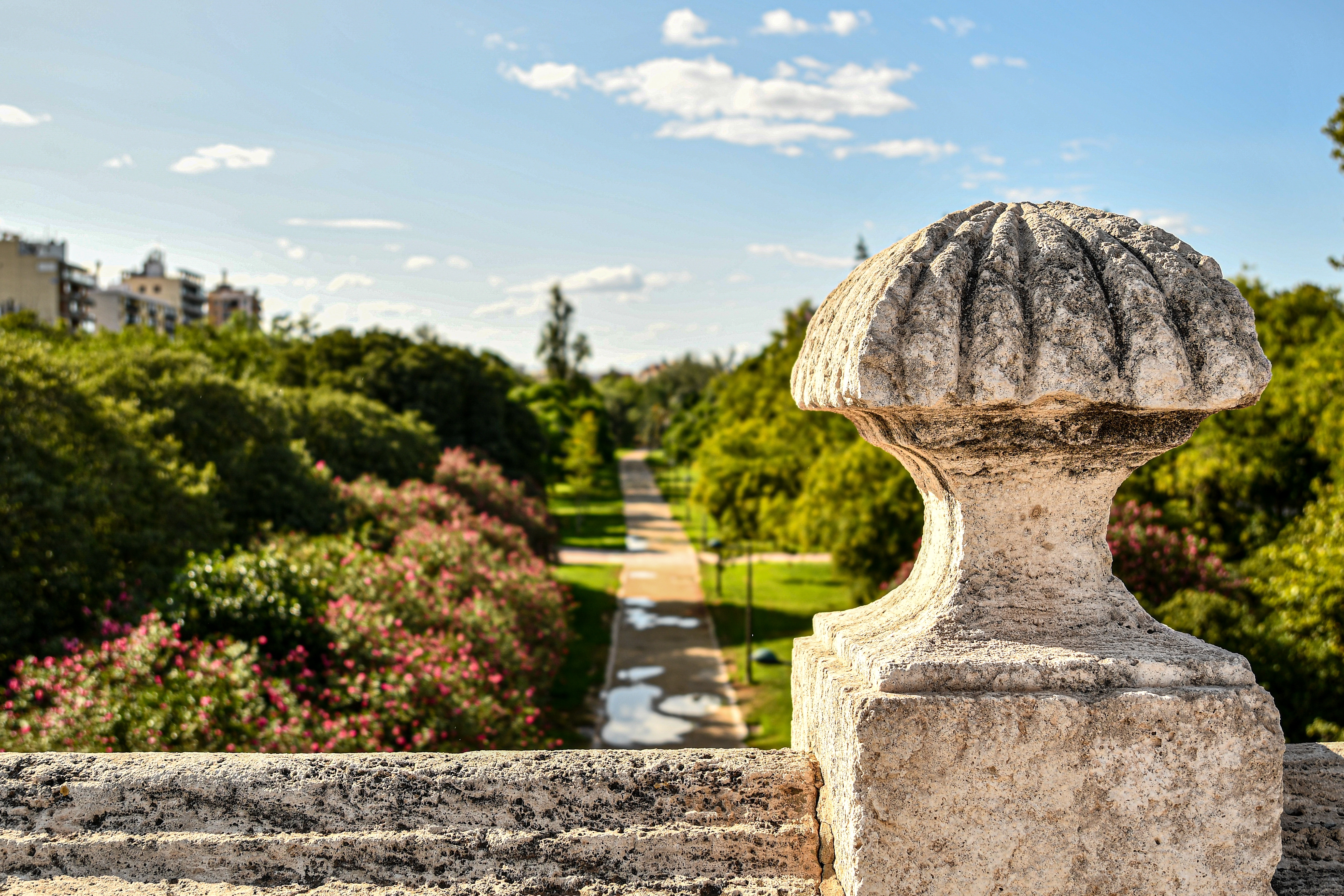 Frodige Turia Gardens i Valencia med smuk stenbalaustrade og blomsterrig sti omgivet af grønne træer - en oase i Spaniens charmerende by