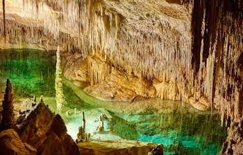 Fascinerende turkisblåt vand i Cuevas del Drach drypstenshuler på Mallorca med imponerende kalkstensformationer og krystalklare underjordiske søer