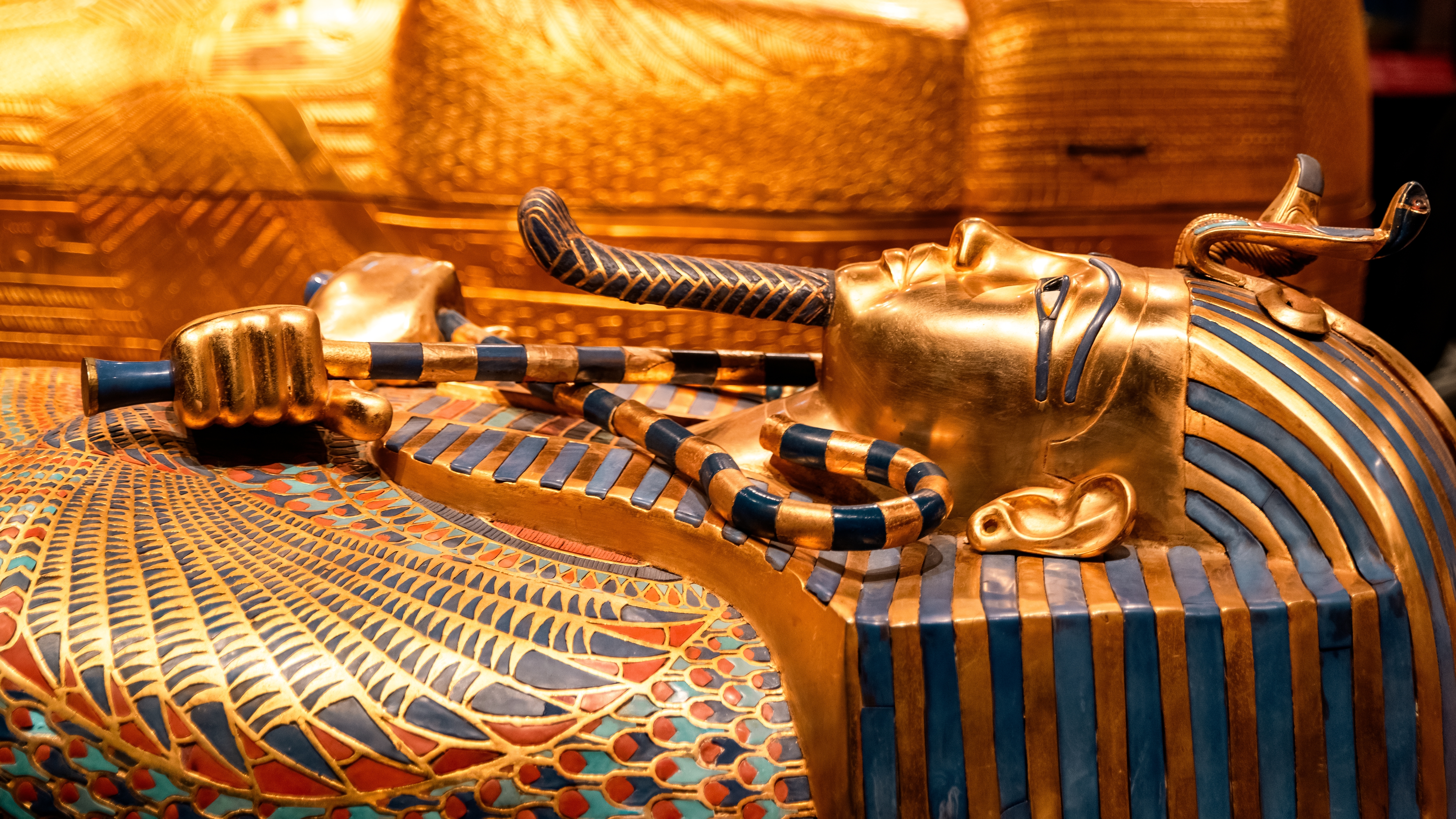 Tutankhamuns gyldne sarkofag med blå indlægsdekorationer og krydsede ceremonielle symboler fra det gamle Egypten