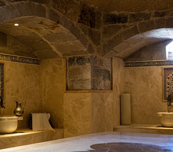 Luksuriøst interiør i et traditionelt tyrkisk hamam i Istanbul med elegante marmoroverflader, dekorative arkitektoniske elementer og stemningsfuld belysning, der skaber en autentisk wellnessoplevelse