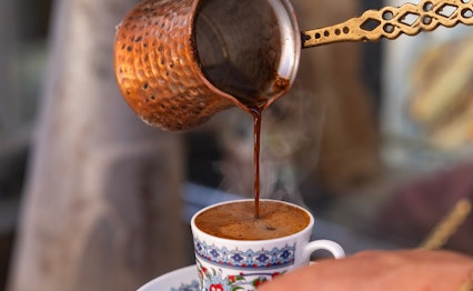 Traditionel tyrkisk kaffe hældes fra en kobberkande (cezve) i en dekoreret kop i Eminönü-kvarteret i Istanbul