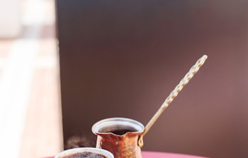 Traditionel tyrkisk kaffe serveret med den søde kadaif-dessert på et rødt bord i en udendørs café i Albanien