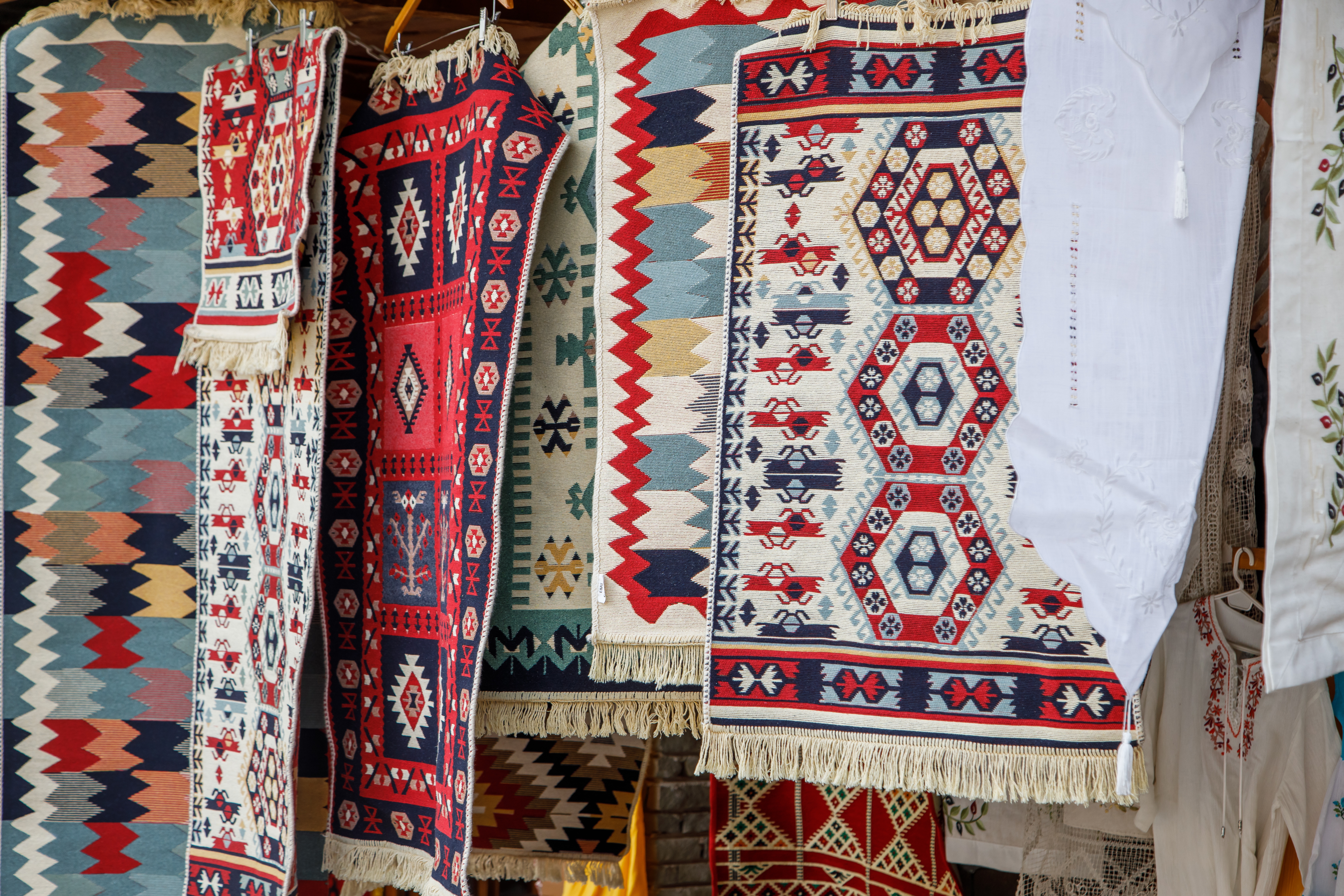 Farverige tyrkiske kilim tæpper med geometriske mønstre hænger på traditionelt marked i Tyrkiet