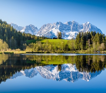 Betagende alpelandskab i Tyrol, Østrig, hvor sneklædte bjerge spejler sig i den idylliske Schwarzsee sø nær Kitzbühel - et perfekt sceneri for naturelskere