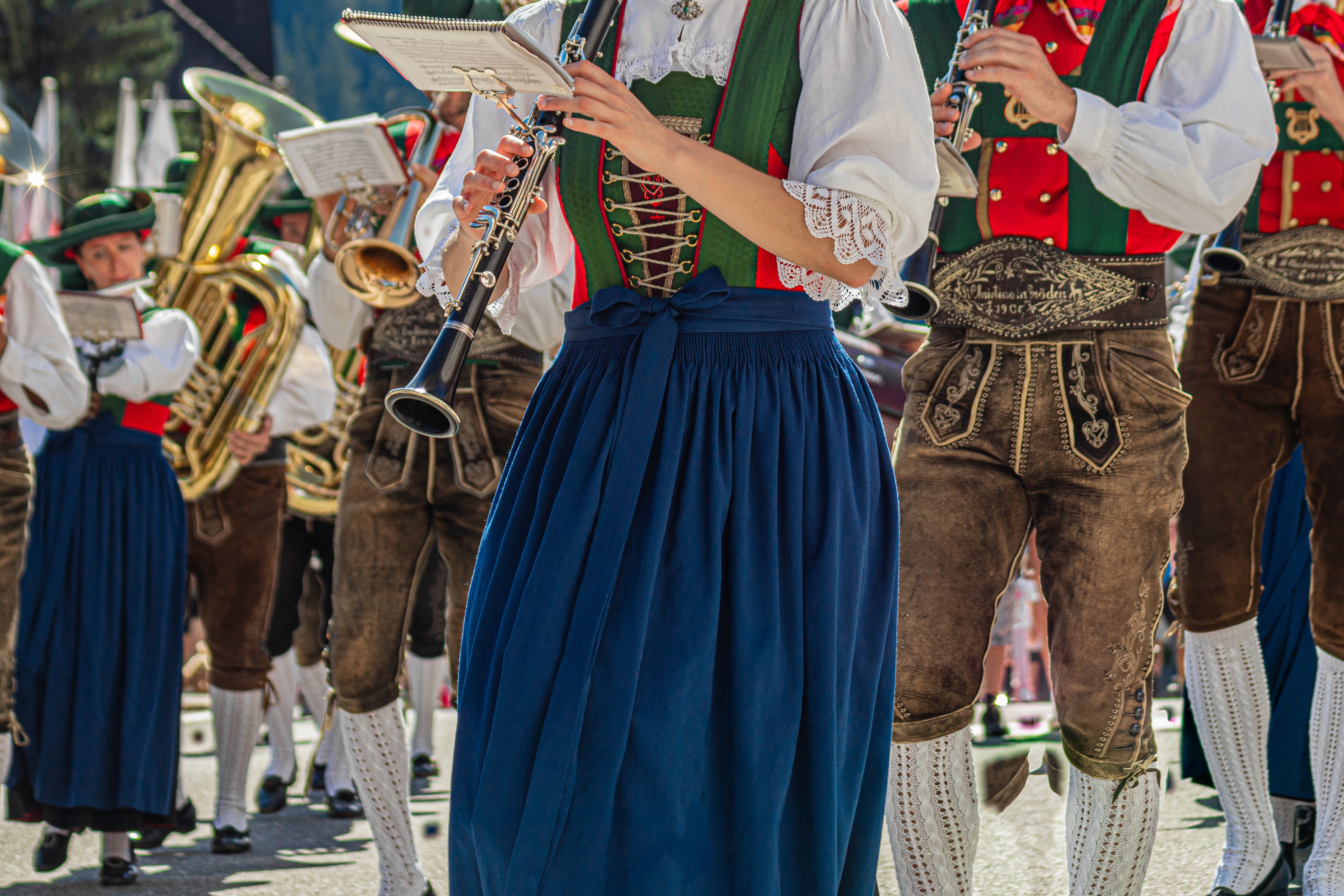 Traditionelle tyroleske musikere i dirndl og lederhosen spiller klarinet og messinginstrumenter under en folkeparade i Val Gardena, Sydtyrol, Italien