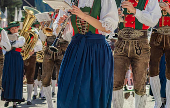 Traditionelle tyroleske musikere i dirndl og lederhosen spiller klarinet og messinginstrumenter under en folkeparade i Val Gardena, Sydtyrol, Italien