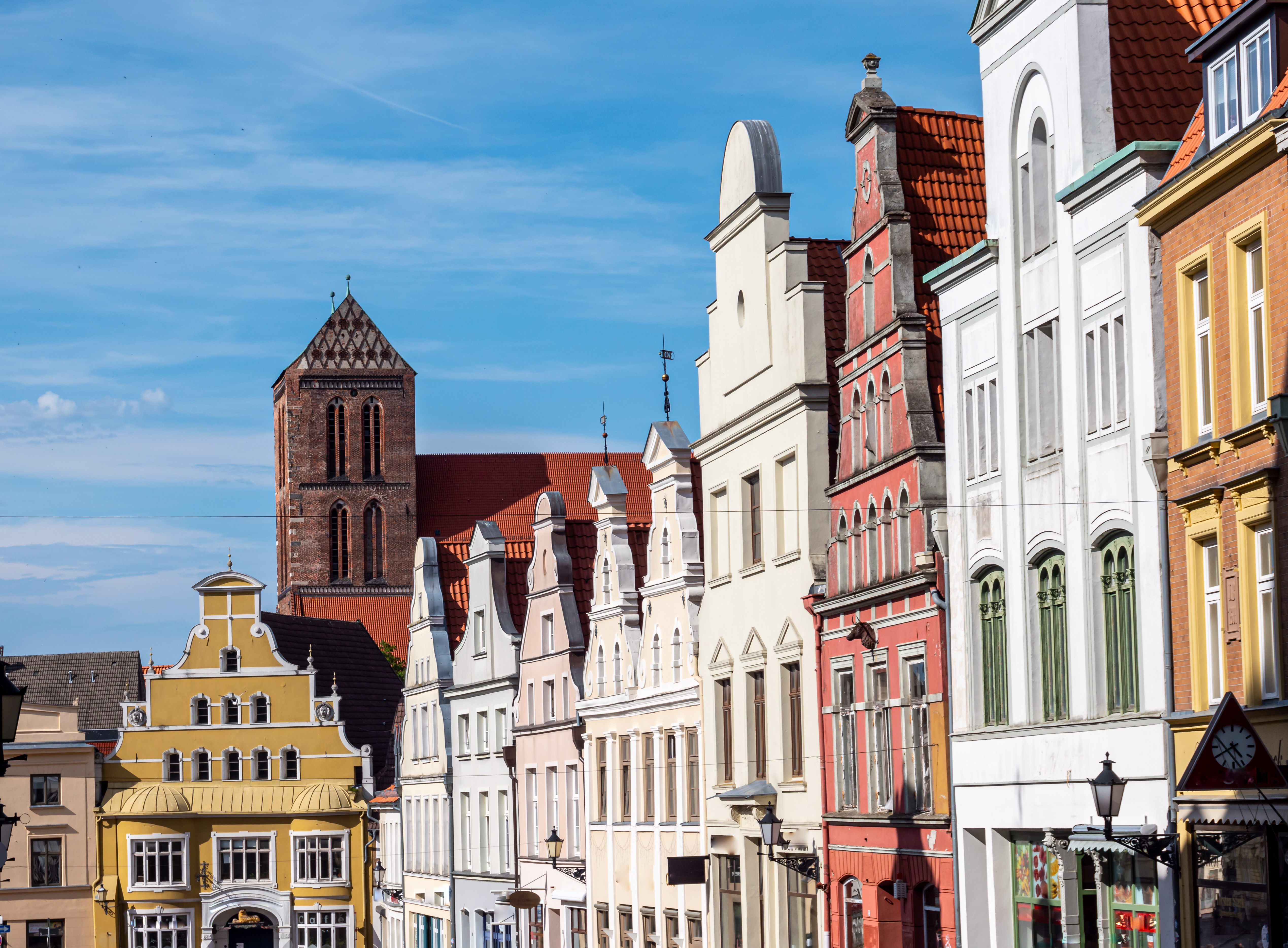 Farverige historiske bygninger og middelalderkirke i tysk hansestads gamle bydel