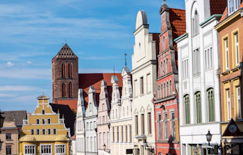 Farverige historiske bygninger og middelalderkirke i tysk hansestads gamle bydel