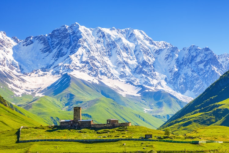 Betagende udsigt over Ushguli landsby med historiske stentårne ved foden af snedækkede Shkhara-bjerg i Øvre Svaneti, Georgien