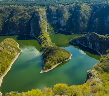 Betagende luftbillede af Uvac-flodens dramatiske slyngninger gennem den dybe kløft i det sydlige Serbien, omgivet af frodige grønne bjerge