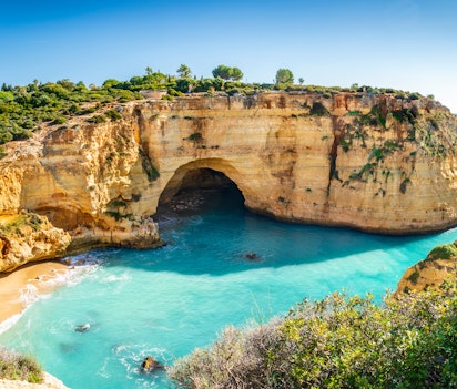 Smuk udsigt over Vale Covo stranden med turkisblåt vand og gyldne sandstensklipper i Algarve, Portugal