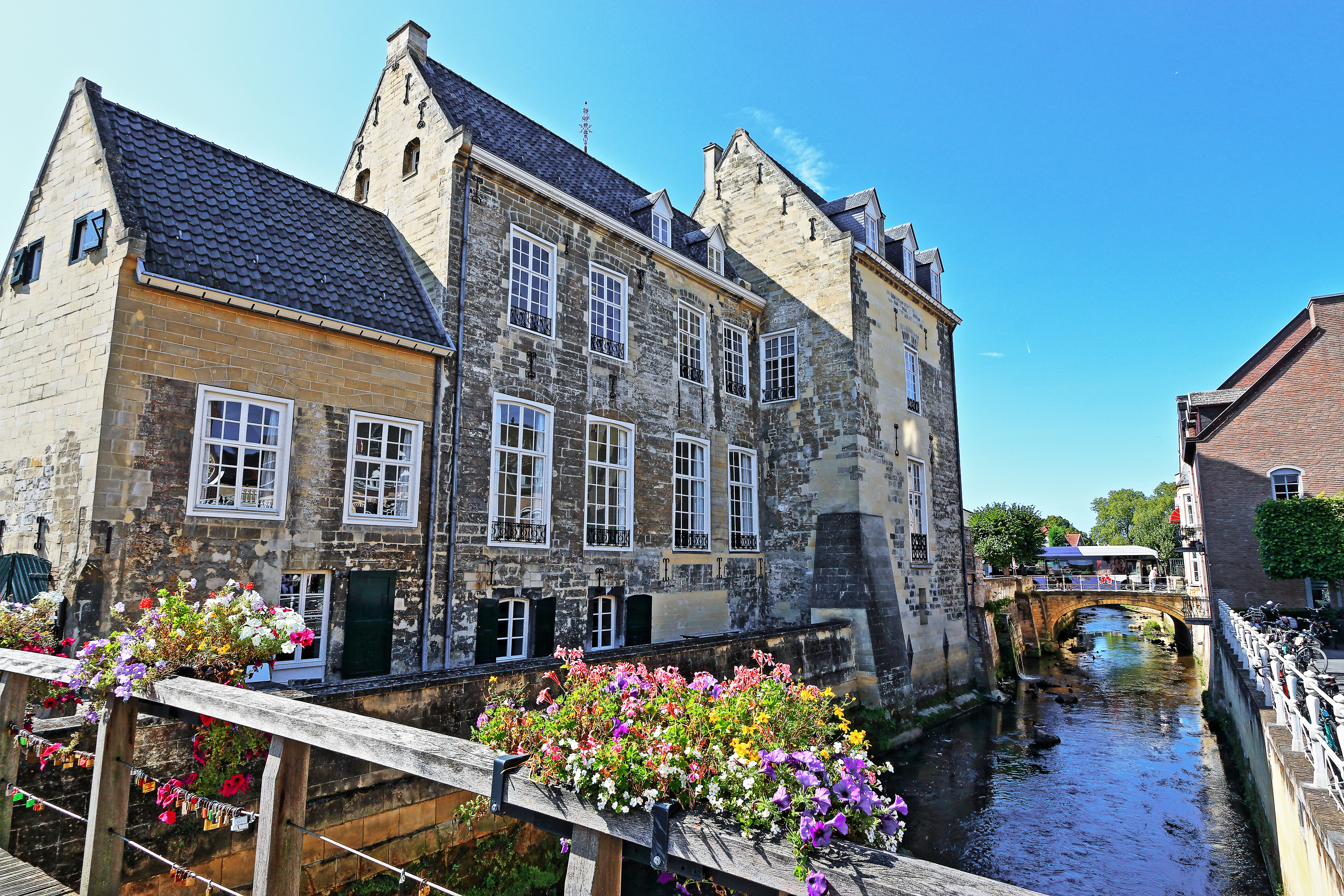 Historisk middelalderborg Burg den Halder langs kanalen i Valkenburg aan de Geul, Limburg, Holland, pyntet med farverige blomster på en træbro