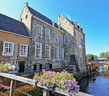 Historisk middelalderborg Burg den Halder langs kanalen i Valkenburg aan de Geul, Limburg, Holland, pyntet med farverige blomster på en træbro