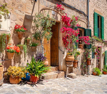 Charmerende historisk bygning i Valldemossa på Mallorca med farverige blomsterkrukker og planter ved indgangen