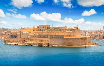 Den historiske fæstning ved Grand Harbour i Valletta, Malta, omgivet af det azurblå Middelhav under en skyfyldt himmel