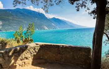 Naturskøn vandrerute ved Gardasøen i Italien med blåt vand, klipper og bjerge under en klar sommerhimmel