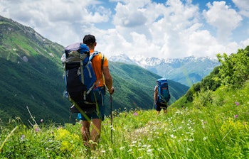 Vandrere med rygsække på bjergsti i Svaneti, Georgien under sommerens smukke bjerglandskab i Kaukasus