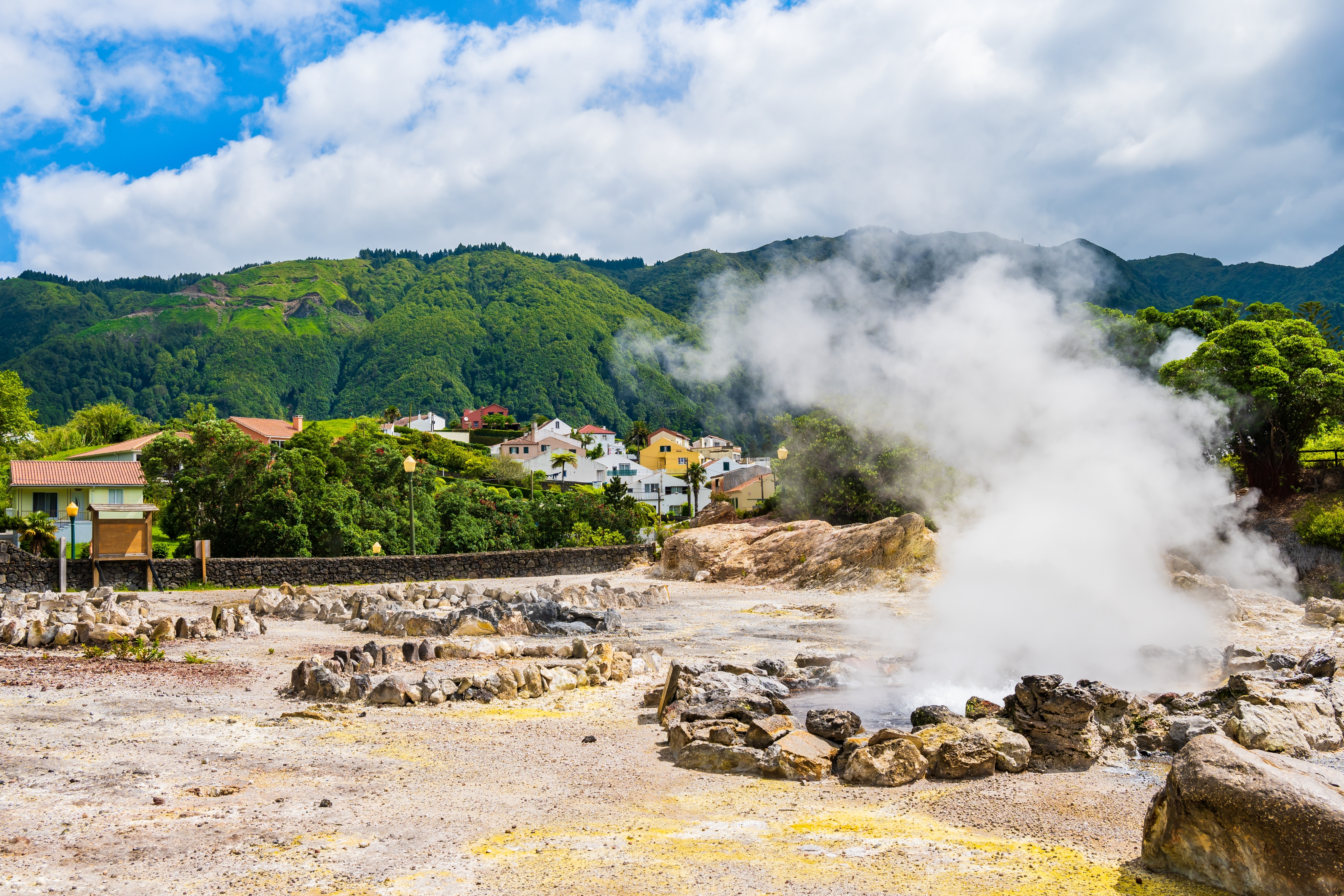 Varme naturlige kilder med dampskyer på Azorerne i Portugal med bjerglandsby