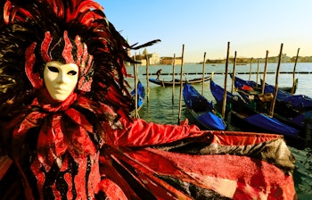 Person i traditionel venetiansk karnevalsdragt med guldmaske på Piazza San Marco under Venedigs berømte karneval i Italien