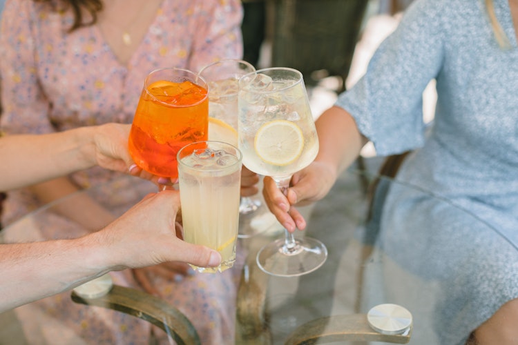 Glade venner skåler med forfriskende cocktails på en hyggelig udendørs café under deres ferie