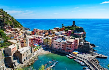 Malerisk udsigt over Vernazza i Cinque Terre med farverige huse på klippesiden og den charmerende lille havn ved det azurblå Middelhav