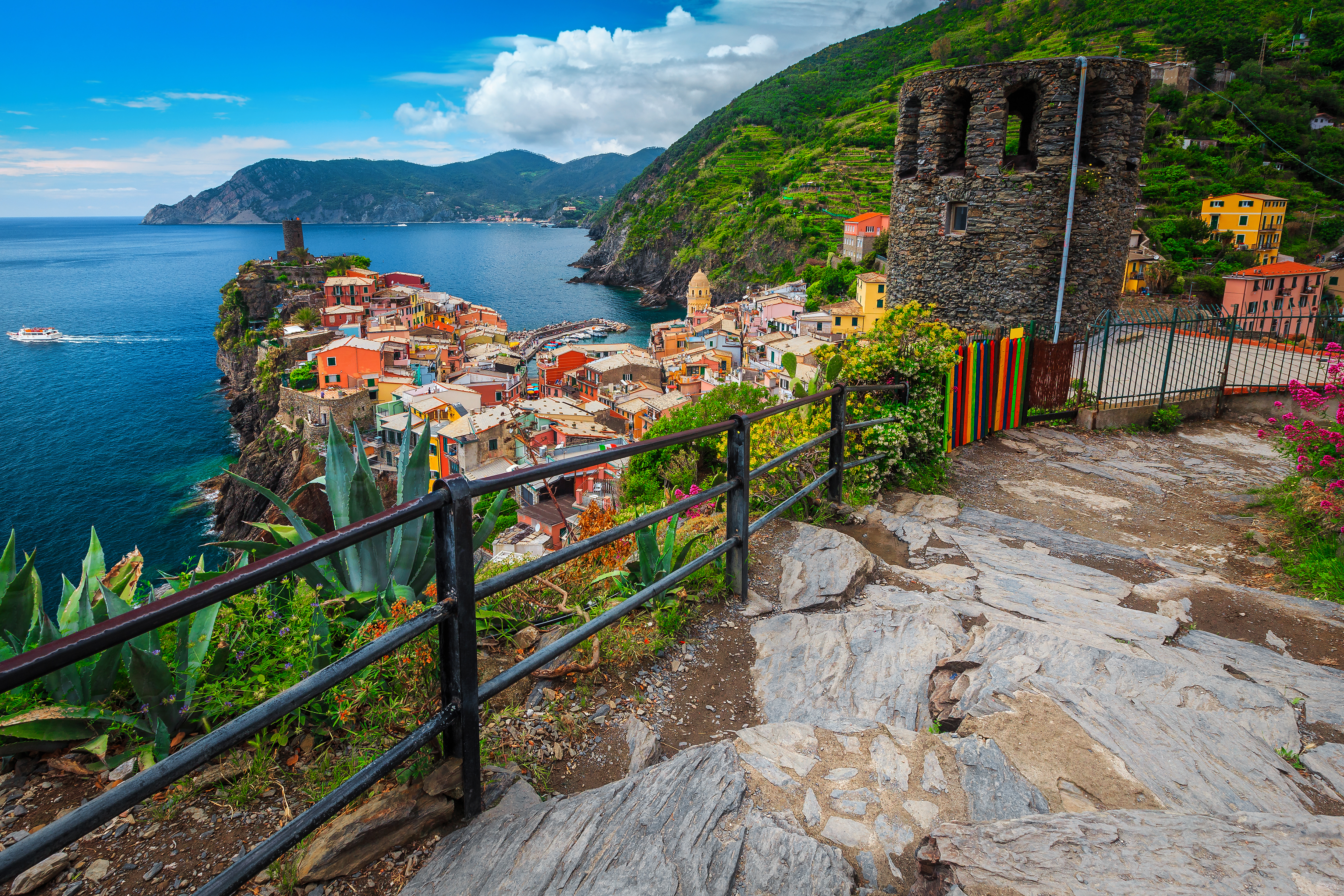 Malerisk udsigt over Vernazza med farverige huse og historisk bastion set fra vandrestien i Cinque Terre, Italien
