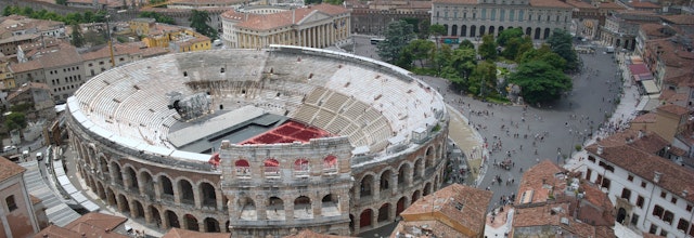Betagende panoramaudsigt over Verona ved solnedgang med den ikoniske Arena di Verona i centrum og byens historiske arkitektur langs Adige-floden
