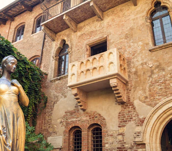 Den berømte bronzestatue af Julie og den ikoniske balkon ved Casa di Giulietta i Verona, Italien, et populært turistmål inspireret af Shakespeares Romeo og Julie, selvom det er en romantisk fantasi