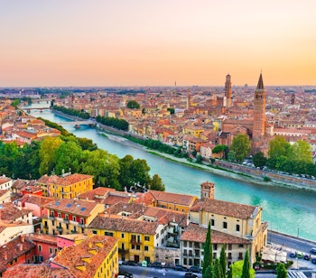 Malerisk solnedgang over Veronas historiske centrum med Adige-floden, middelalderarkitektur og ikoniske tårne i Norditalien