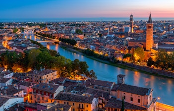 Betagende luftfoto af Verona ved solnedgang med historiske bygninger og Adige-floden, hvor du kan opleve verdensberømte operaforestillinger