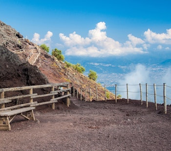 Turiststi på toppen af Vesuv-vulkanen nær Pompeji med trægelænder og betagende udsigt over Napoli-bugten