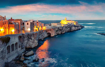 Spektakulær solnedgang over den middelalderlige by Vieste på en klippefyldt halvø i Gargano Nationalpark ved Adriaterhavet i Puglia
