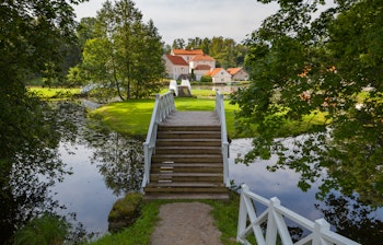 Et smukt sommerlandskab af Vihula Herregård i Estland med en rolig dam og frodig natur.