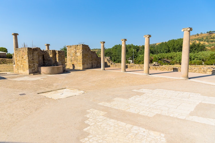 Historisk kolonnade i gården af Villa Romana Del Casale på Sicilien med velbevarede romerske søjler fra det 4. århundrede, et UNESCO verdensarvssted
